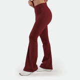 a fit woman stand at right and wearing flared legging pomegranate with shoes white  