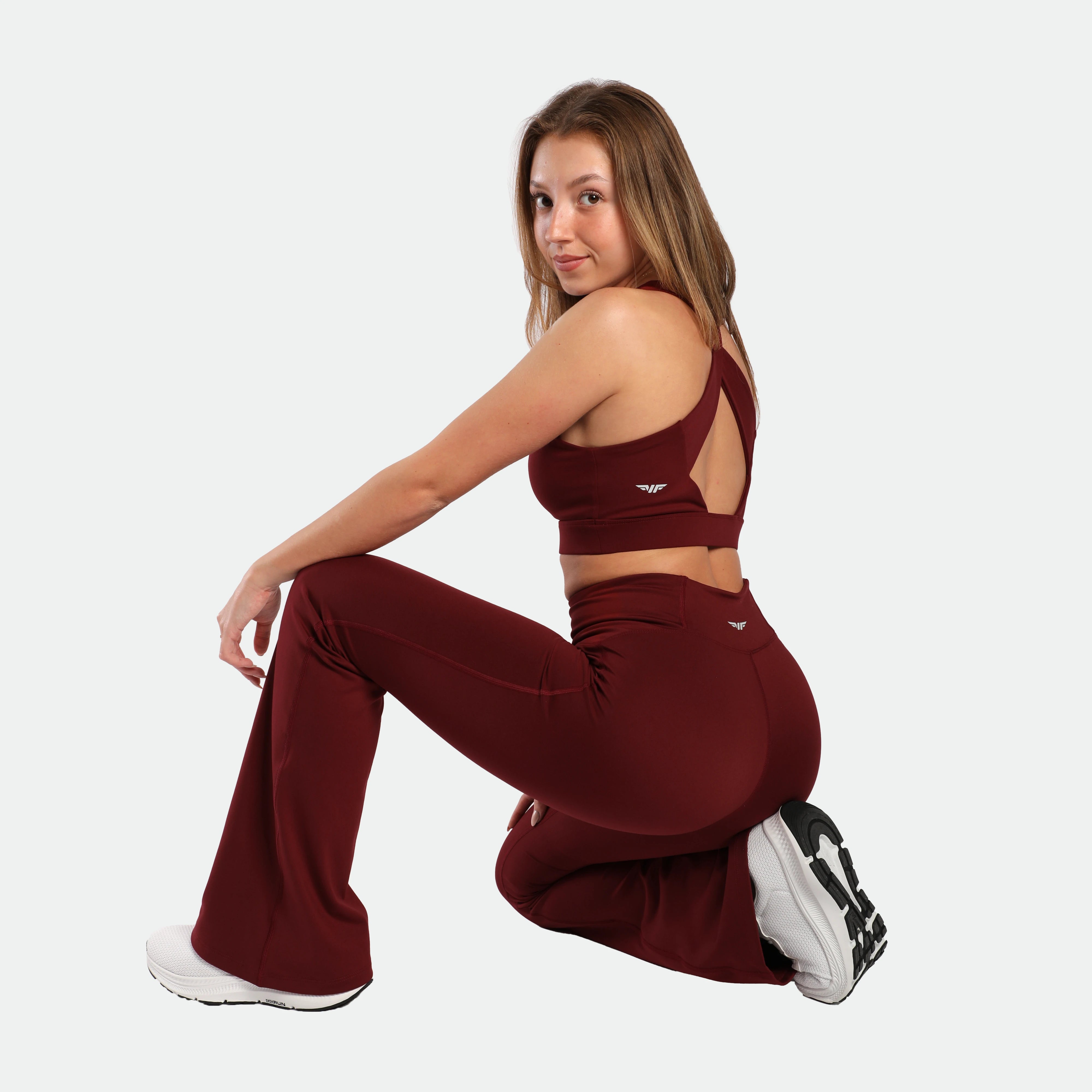 a fit woman sits on it and wearing bra and flared legging pomegranate red ,pus the shoes 