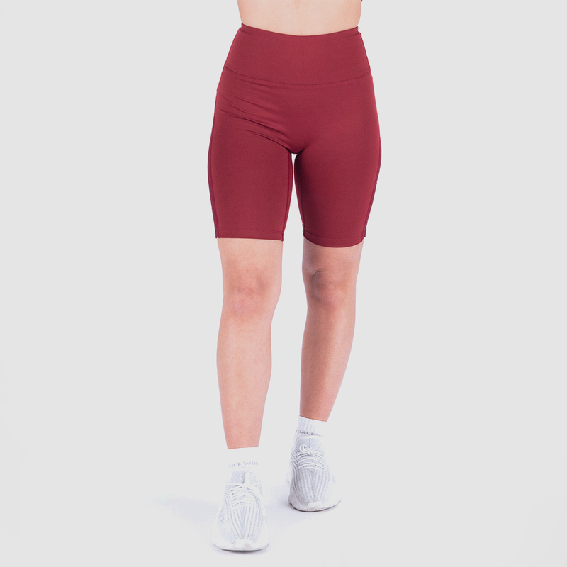 a fit woman wearing seamless short red with shoes and socks white plus the background is light grey 