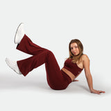 Woman in maroon outfit with white shoes on a plain background