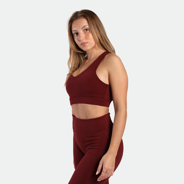 a fit woman stand at right and wearing matching set pomegranate ,bra and  flared legging 