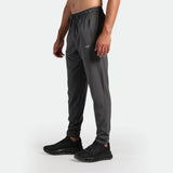 a fit man stand at right and wearing jogger pants grey ,plus the shoes black 