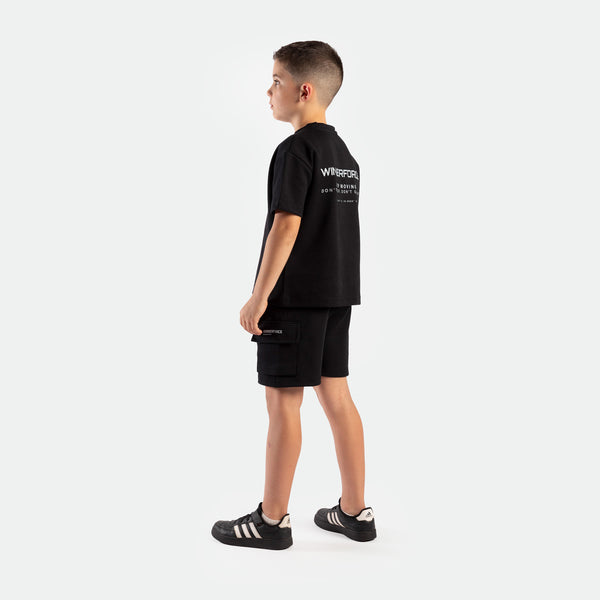 a back view for boy young wearing matching set black ,t-shirt with logo and short with tow pocket ,plus the shoes 