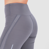 Close-up of a person wearing high-waisted gray athletic leggings with a subtle striped side detail, highlighting fit and smooth texture.