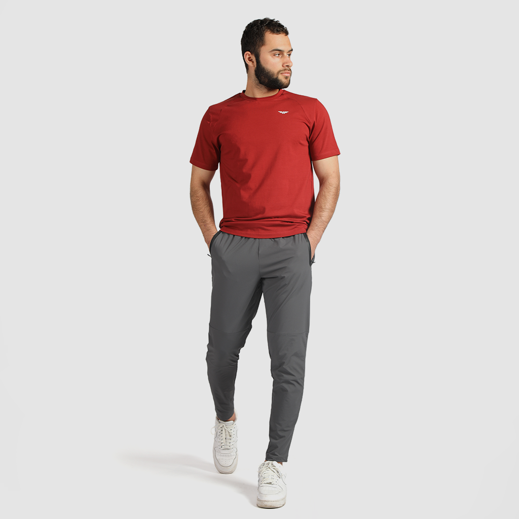 a fit man wearing t-shirt red with pants grey ,plus the shoes white 