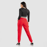a back view for fit woman wearing crop top black with red jogger pants  and 
shoes black ,plus the background is light grey 