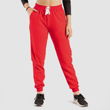 a fit woman wearing  red jogger pants with shoes black ,plus the background is light grey  
