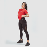 a fit woman wearing  t-shirt red with logo with logo white  and legging black with little mesh fabric black ,plus she wearing a sneakers  black 
