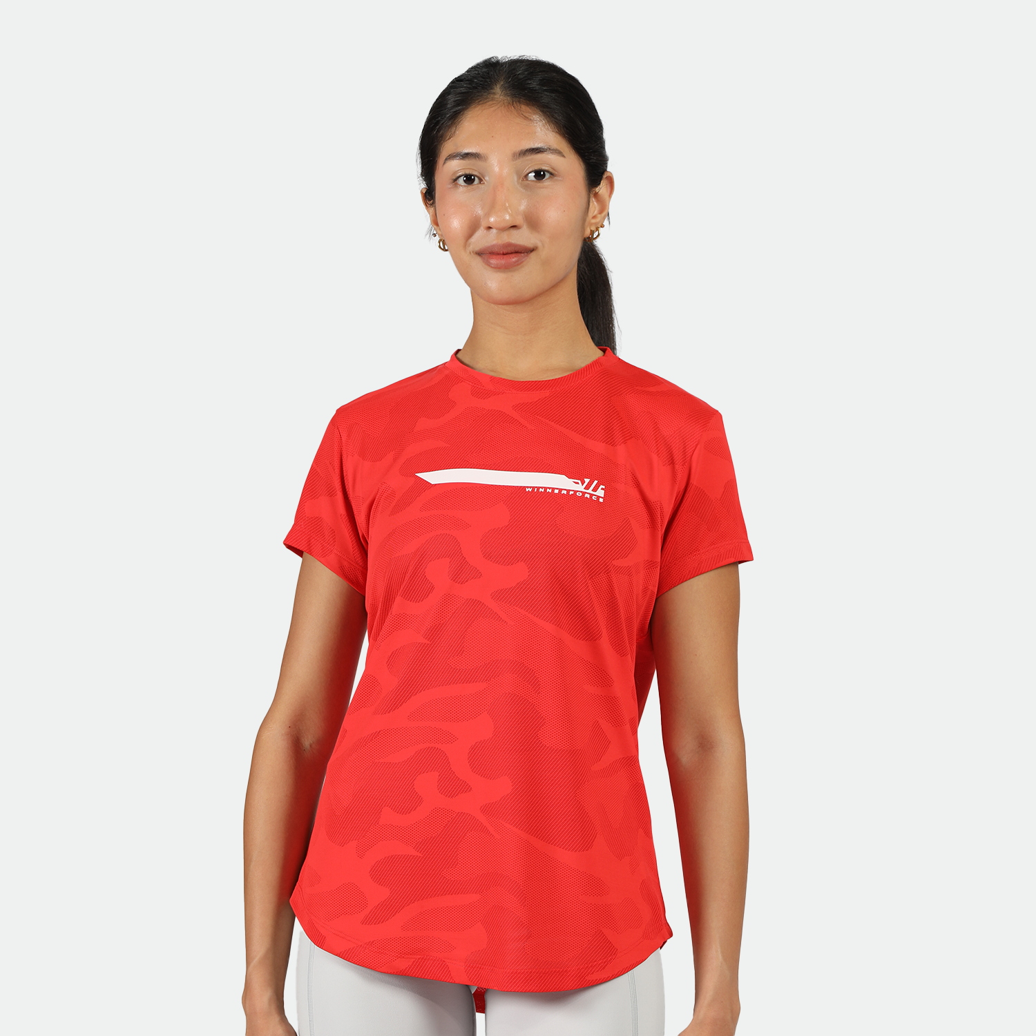 a fit woman look at the camera with smile ,she wearing camo red t-shirt with short grey 