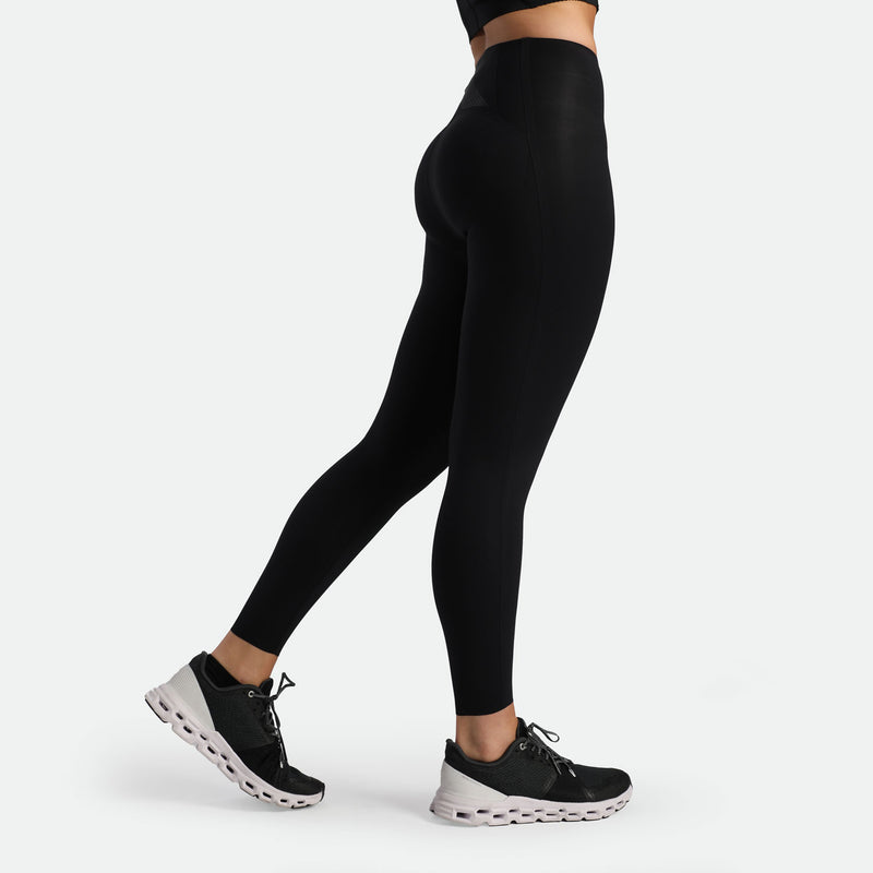 a fit woman stand at right and wearing legging black with shoes black 