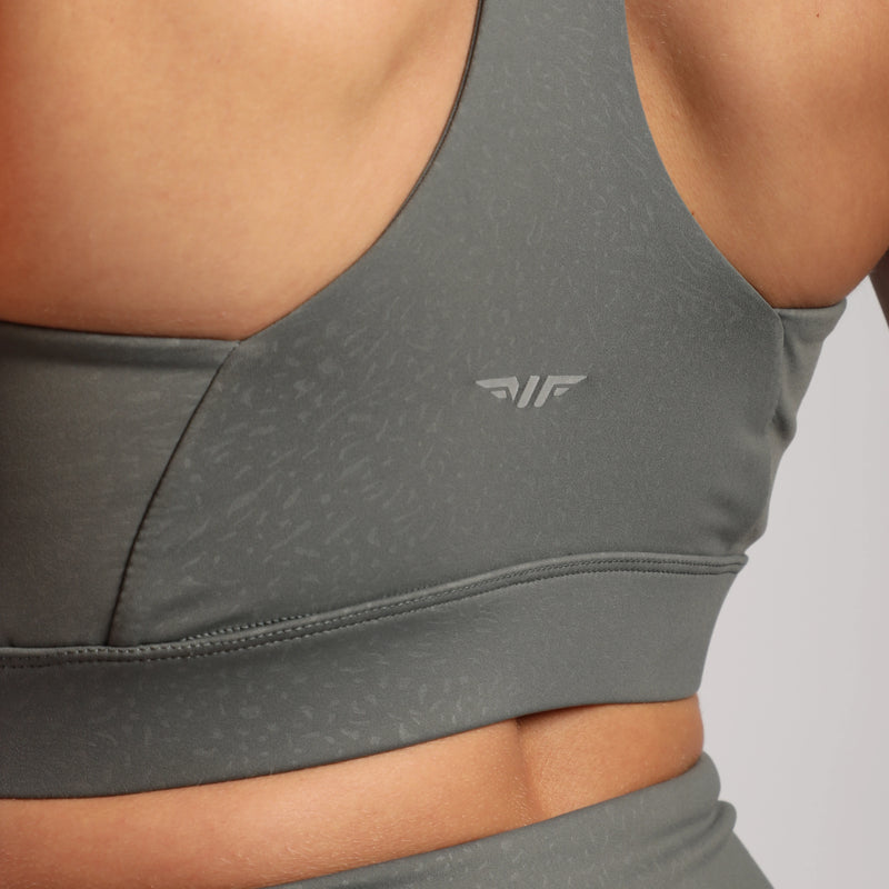 close up view for fit woman wearing bra  sage grey terrazzo with logo in half 