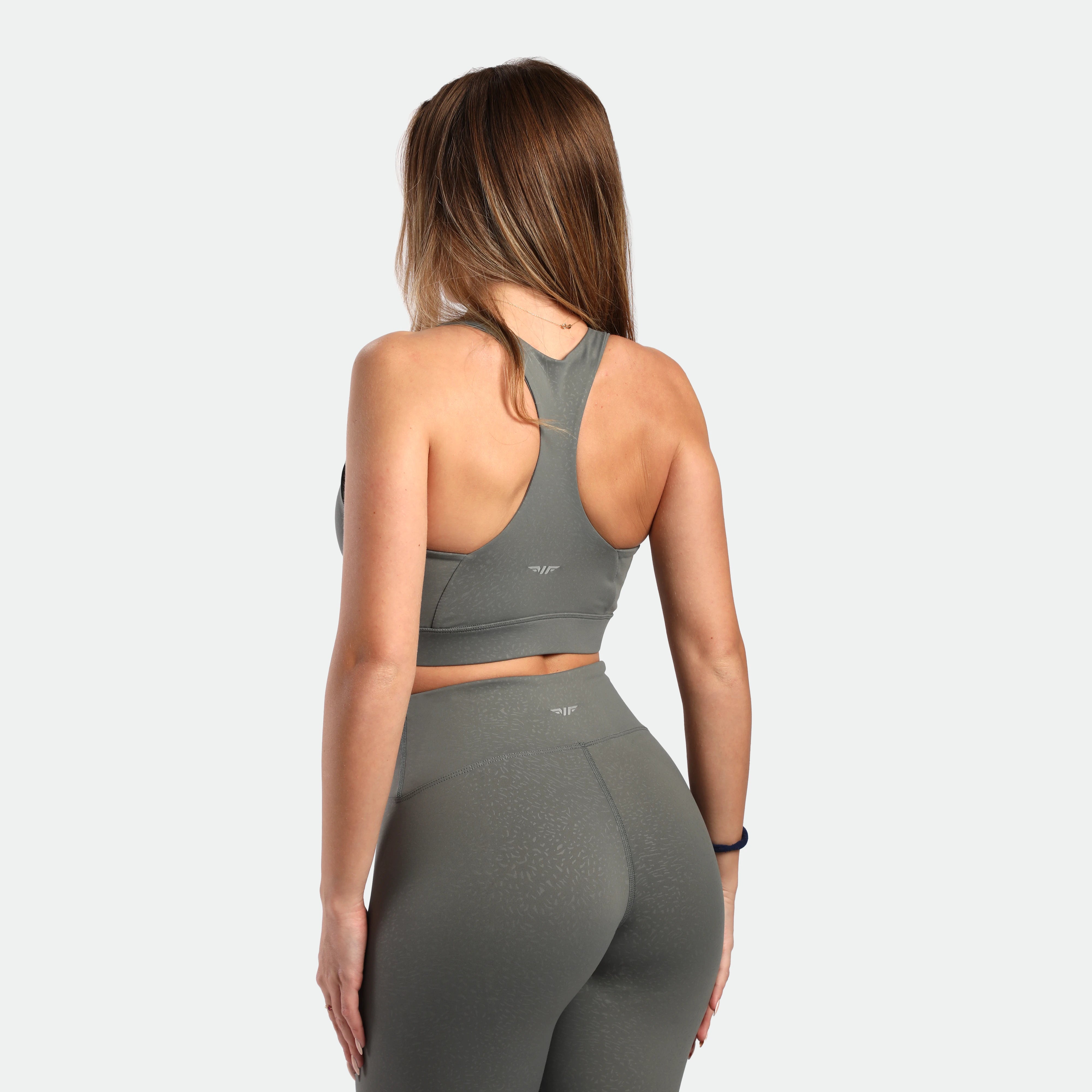 a back view for fit woman wearing matching set sage grey terrazzo bra and legging 
