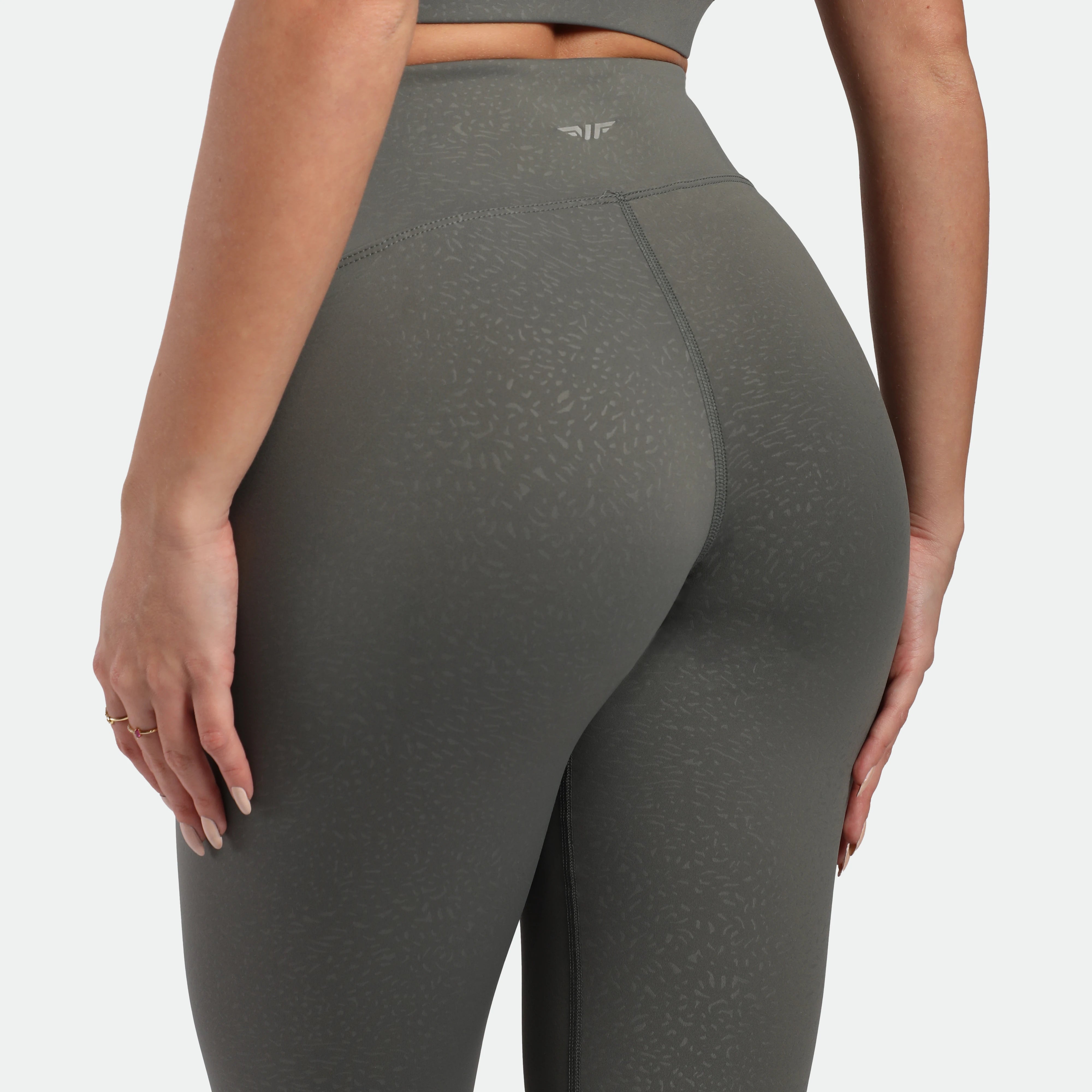 close up view for fit woman wearing legging sage grey terrazzo plus the logo in half 