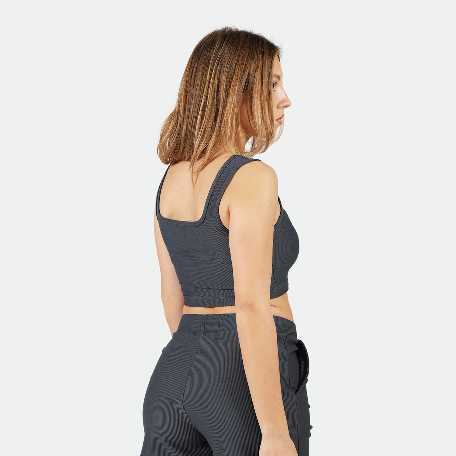 a back view for fit woman wearing  crop top and short grey 
