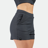 a fit woman stand at right and wearing matching sport bra and short grey ,plus the background is light grey