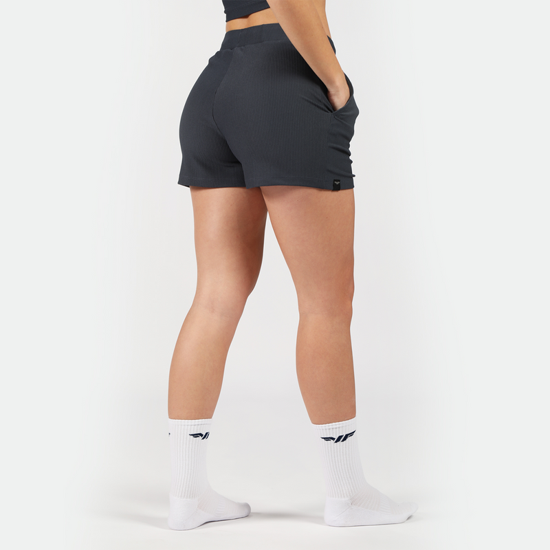 a back view for fit woman wearing short grey with socks white ,plus the background is light grey 
