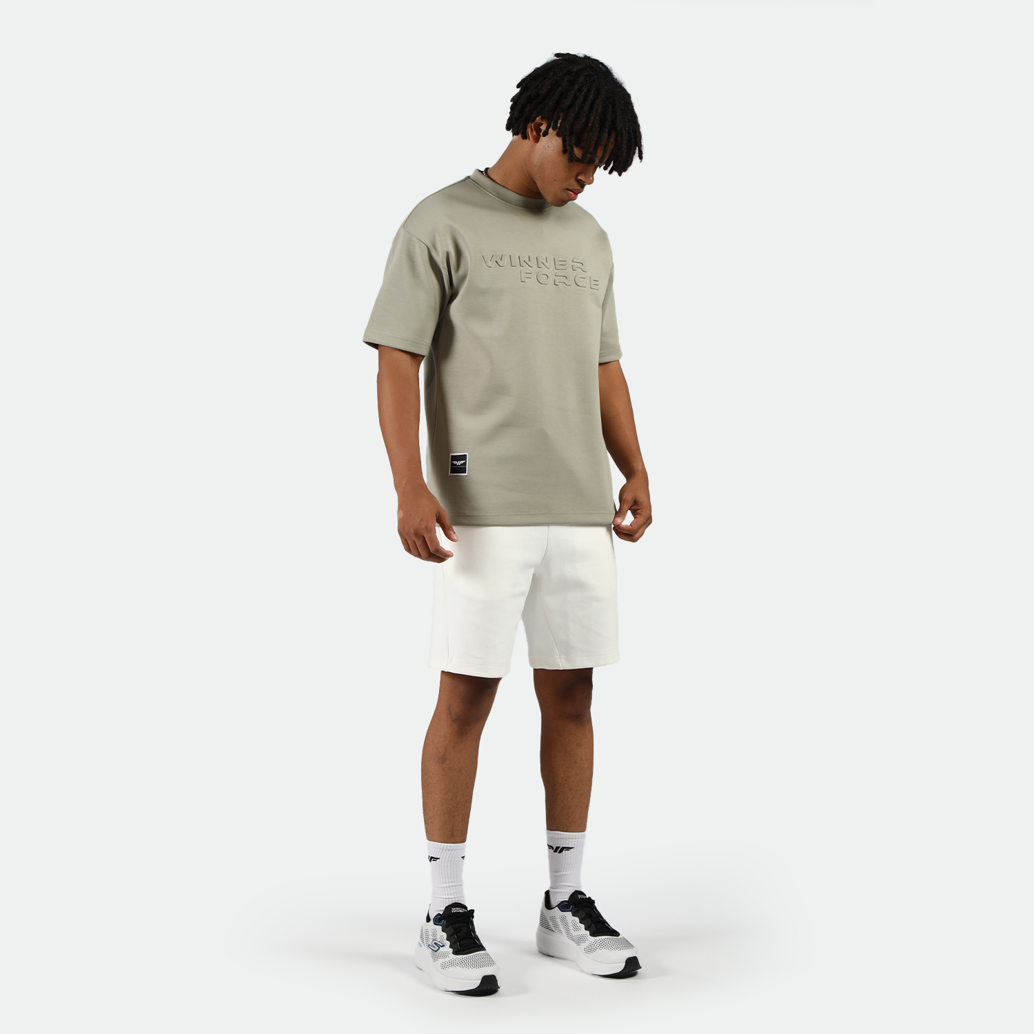 a fit man look down and wearing t-shirt seagrass green with logo and short white ,plus socks white with shoes white 