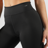 a fit woman wearing legging black with background is light grey 