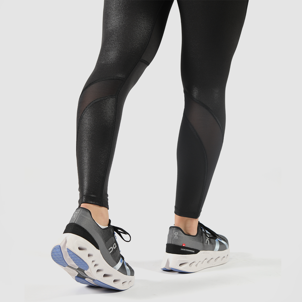 a fit woman  stand  at right and wearing  legging black   ,she wearing shoes  mix color , plus the background is light grey  