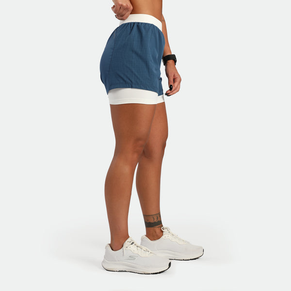 Person wearing blue and white athletic shorts on a plain background