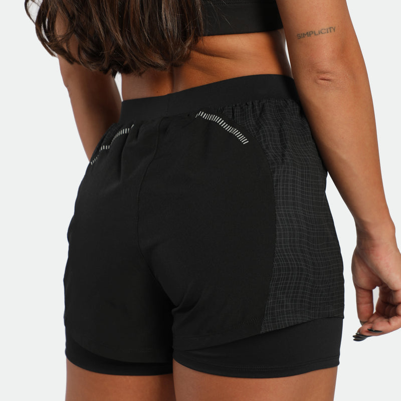 Person wearing black athletic shorts on a plain background