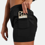 Person wearing a black athletic outfit with a phone in a pocket on a white background