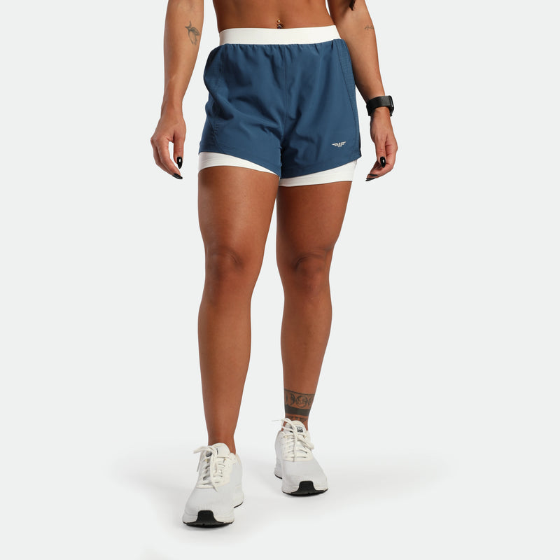 Person wearing blue athletic shorts with white accents on a white background