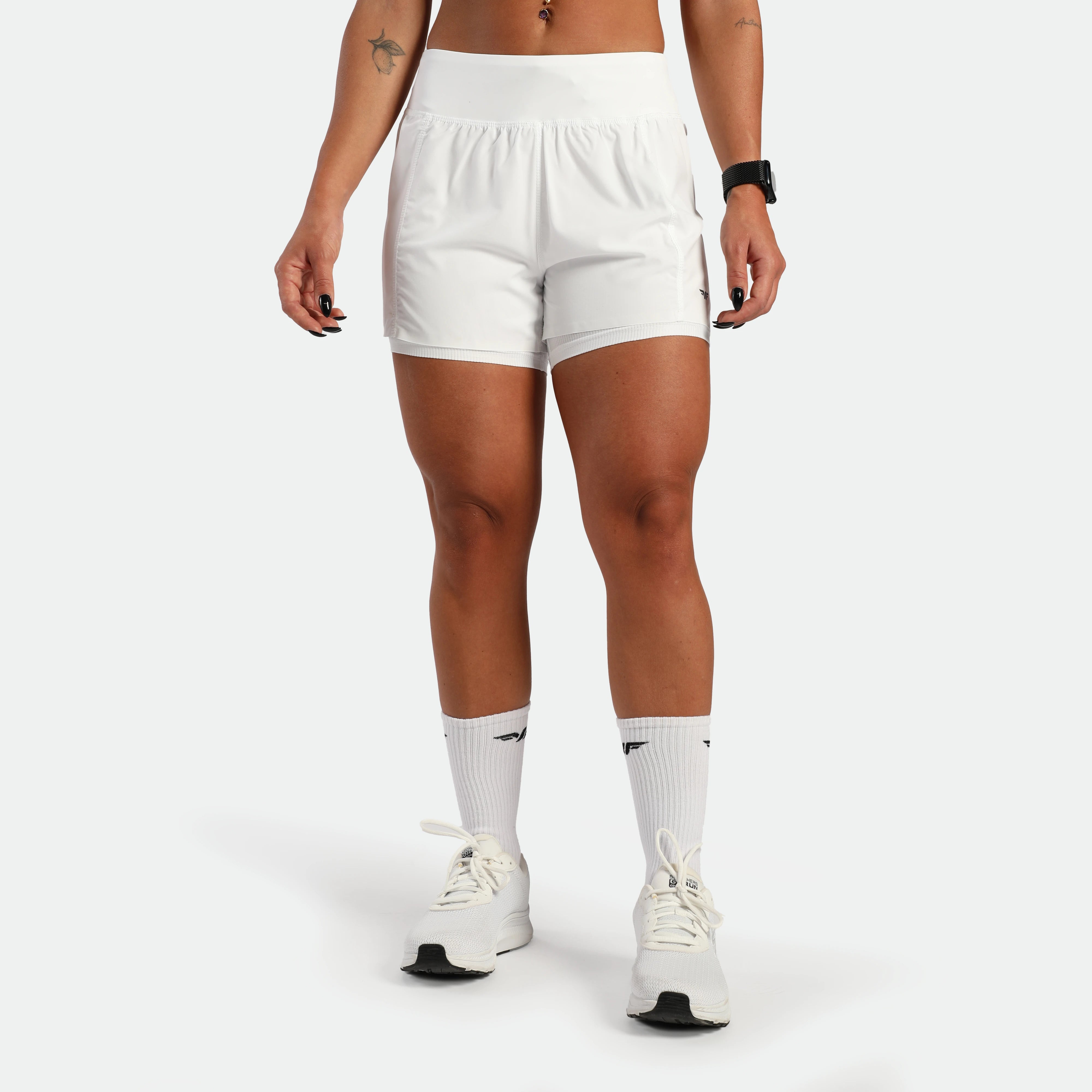 Person wearing white athletic shorts and socks on a plain background