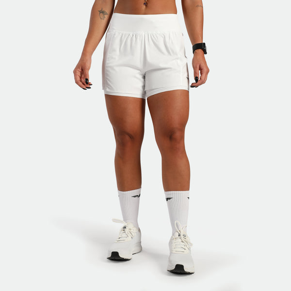 Person wearing white athletic shorts and socks on a plain background