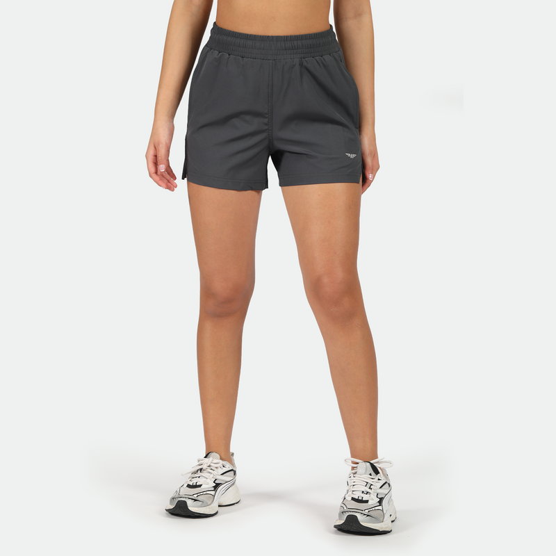 a fit woman wearing grey short with logo ,and wearing shoes ,plus the background is light grey 