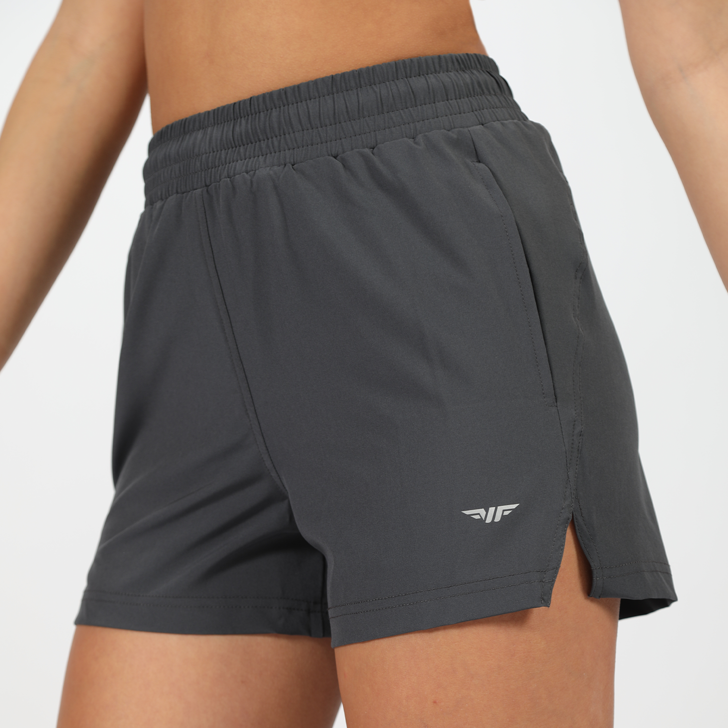 a close-up view for fit woman wearing short grey with logo, plus the background is light grey 