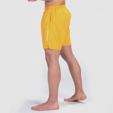 a fit man stand at right and wearing short canary yellow  with logo 