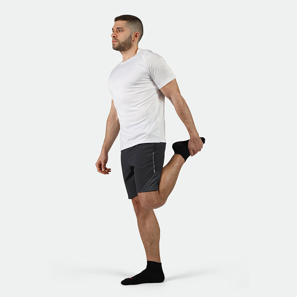 a fit man stand at right with pose sports  and wearing t-shirt  white with short  phantom  grey and socks black