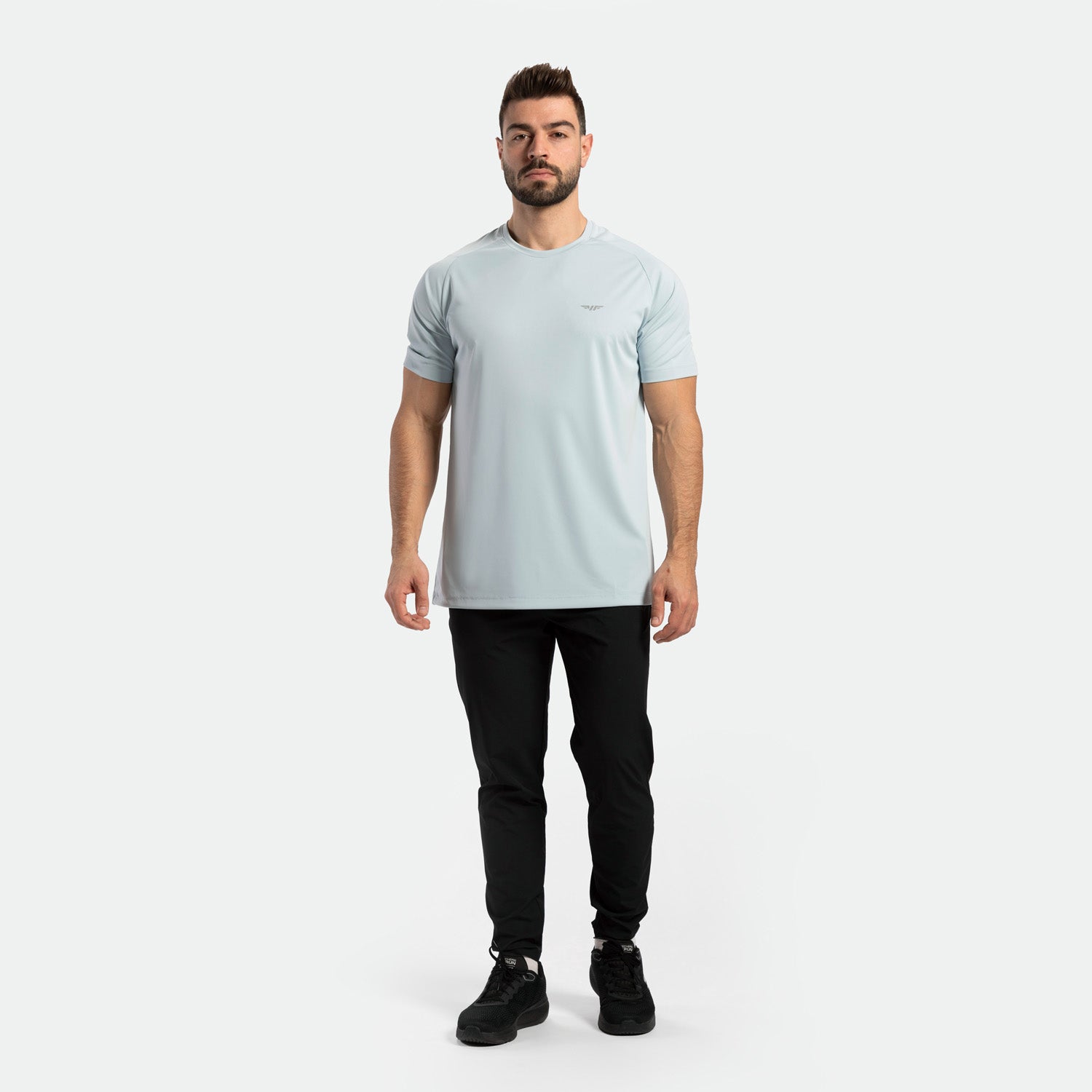 a fit man wearing t-shirt sky blue with pants black ,plus the shoes black 