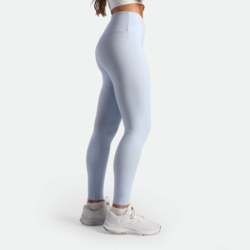 a fit woman stand at right  wearing legging sky blue with shoes  white 