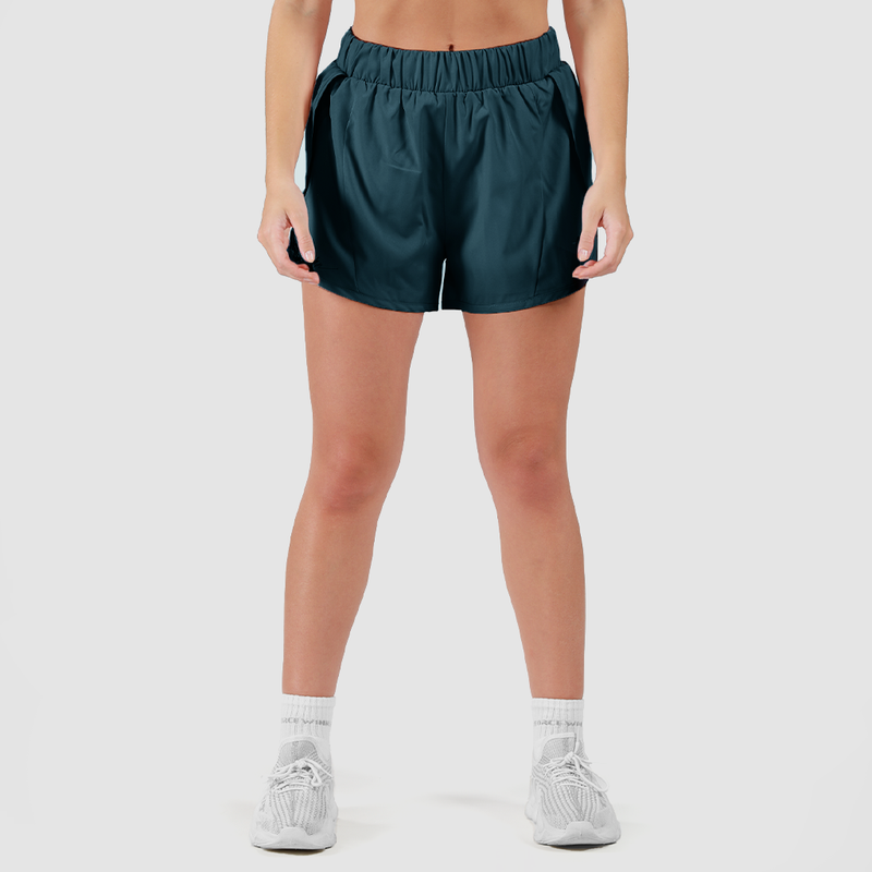 a fit woman wearing stargazer blue  short with white shoes ,plus the background is light grey 