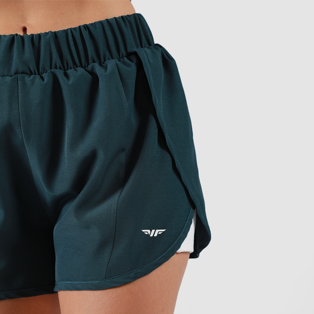 close - up view for fit woman wearing short  2 in 1 green with logo, plus the background is light grey 