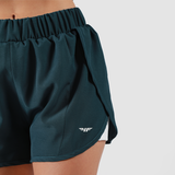 close - up view for fit woman wearing short  2 in 1 green with logo, plus the background is light grey 