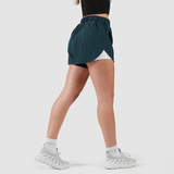 a fit woman stand at right and wearing stargazer blue  short 2 in 1 with shoes white 