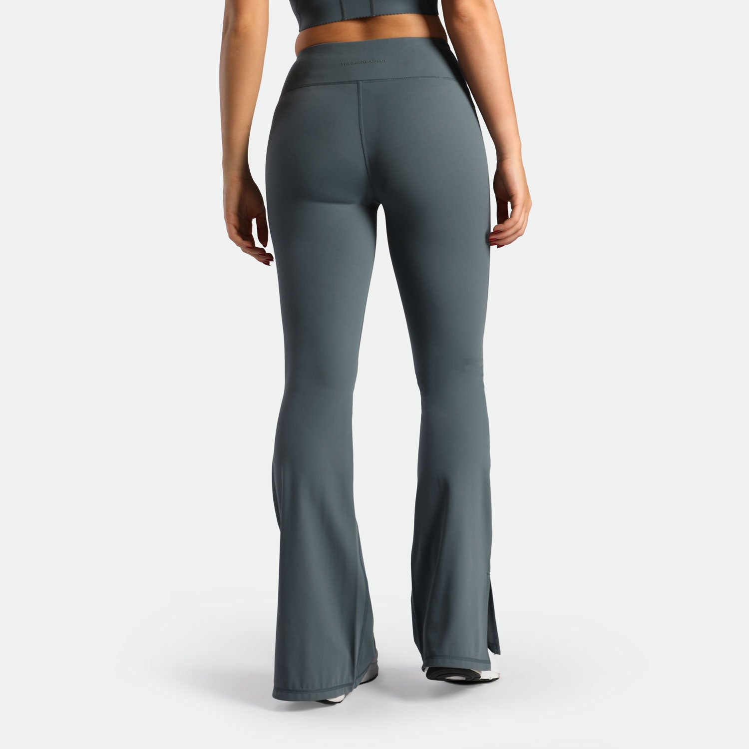 a back view for fit woman wearing flared legging stormy grey with shoes 