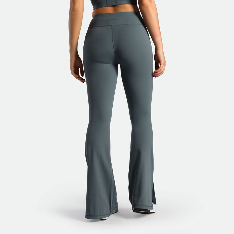a back view for fit woman wearing flared legging stormy grey with shoes 