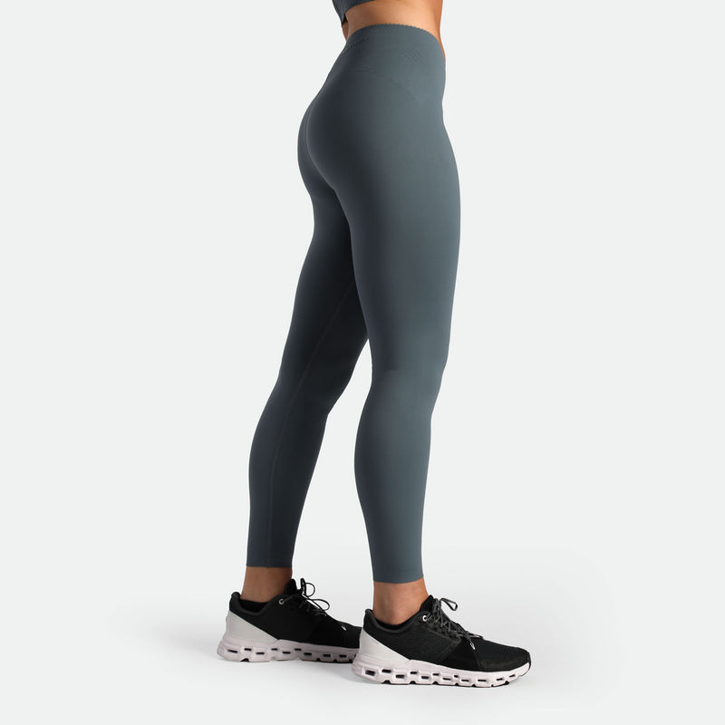 a fit woman stand at right and wearing legging stormy grey with shoes 