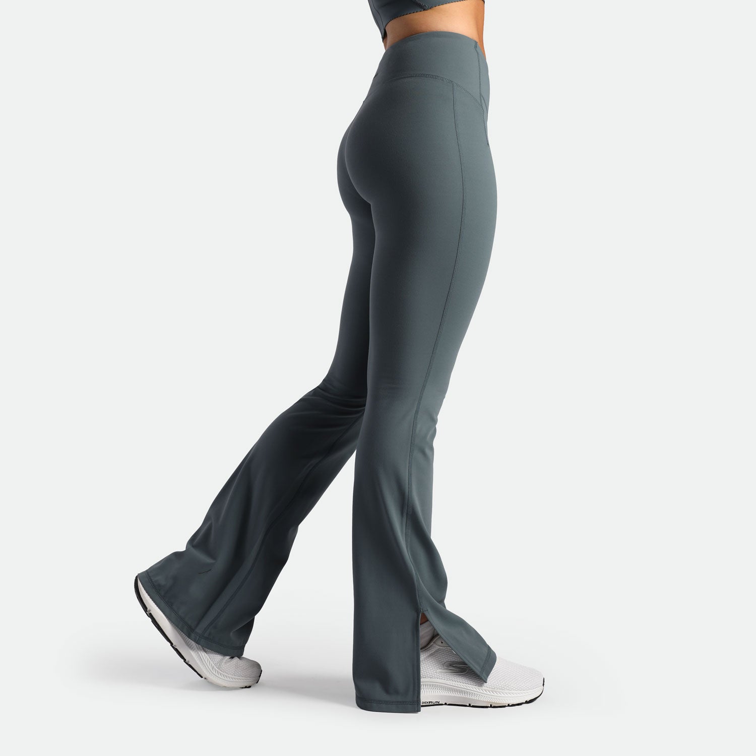 a fit woman stand at right and wearing flared  legging stormy grey with shoes white