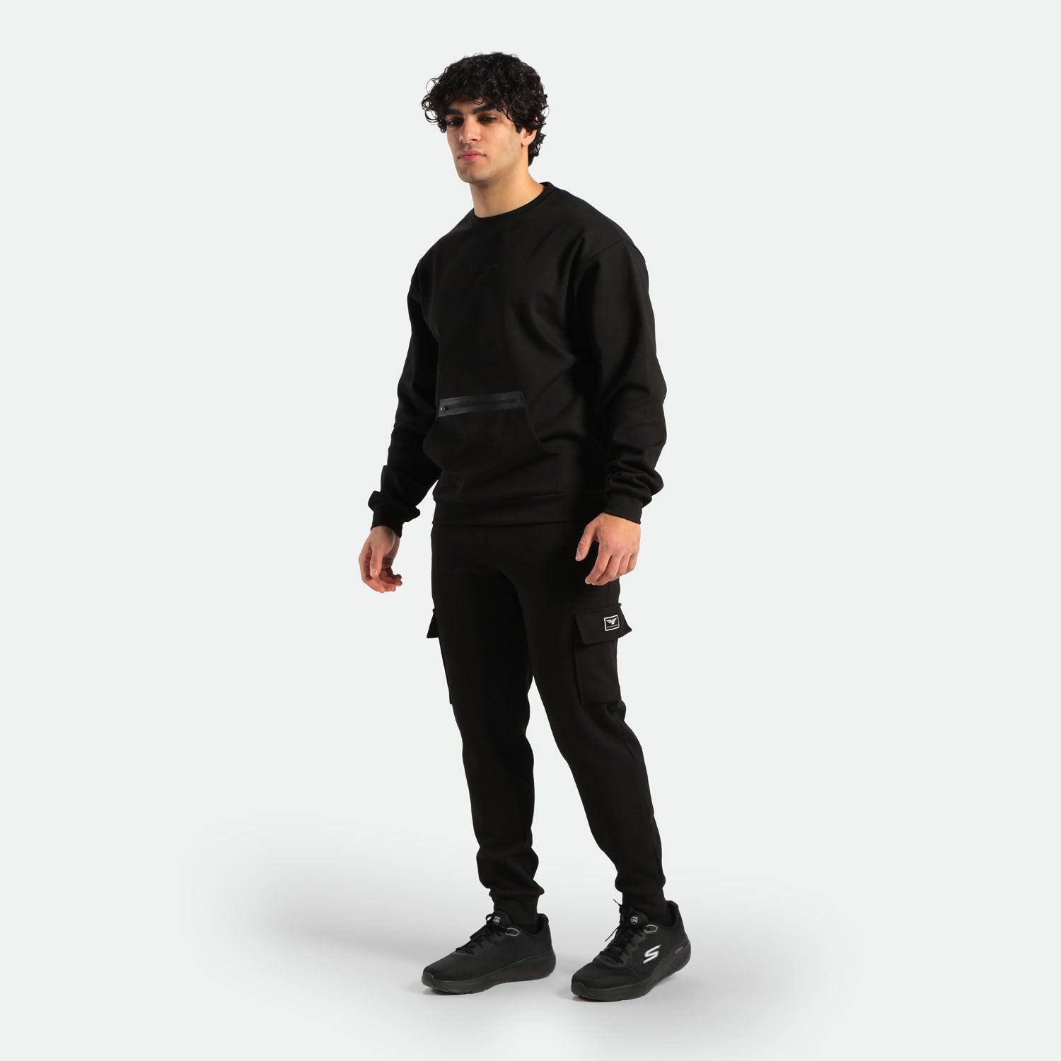 a fit man stand at right and wearing sweatshirt black and jogger pants ,plus the shoes black 