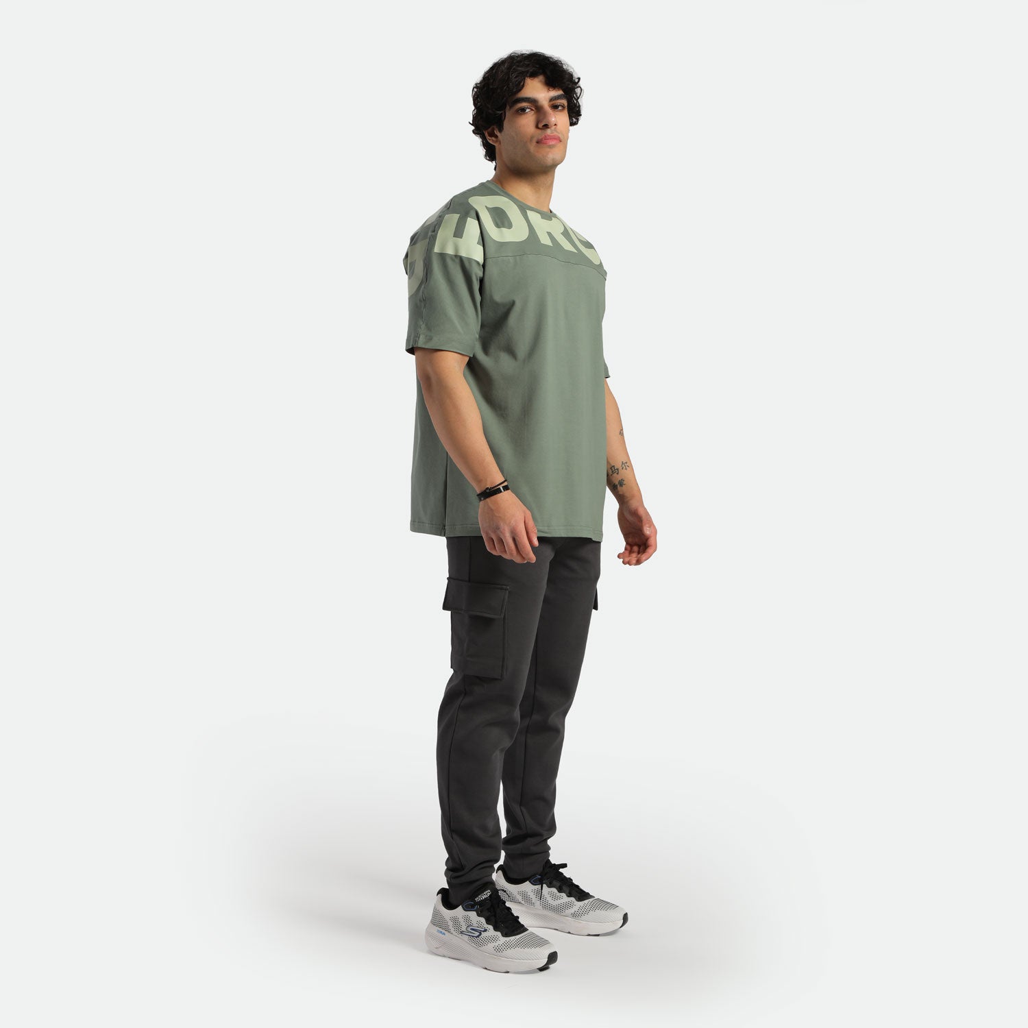 a fit man wearing t-shirt agave green with logo and pants black , plus shoes 