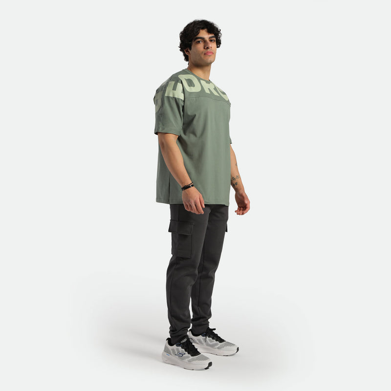 a fit man wearing t-shirt agave green with logo and pants black , plus shoes 