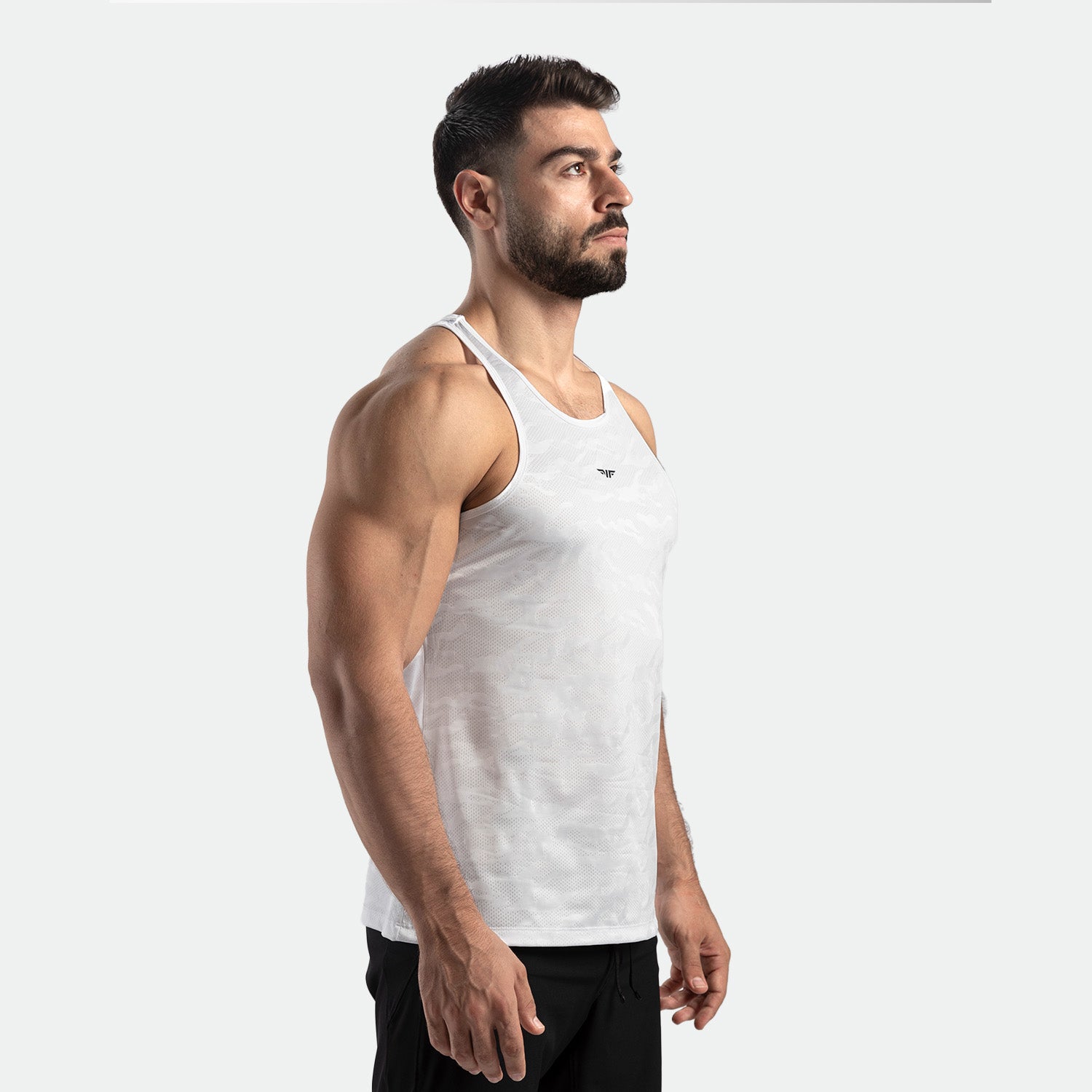 a fit man stand at right and wearing tank white with pants black 