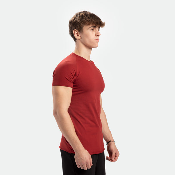 a fit man stand at right and wearing t-shirt tomato dark red with pants black 