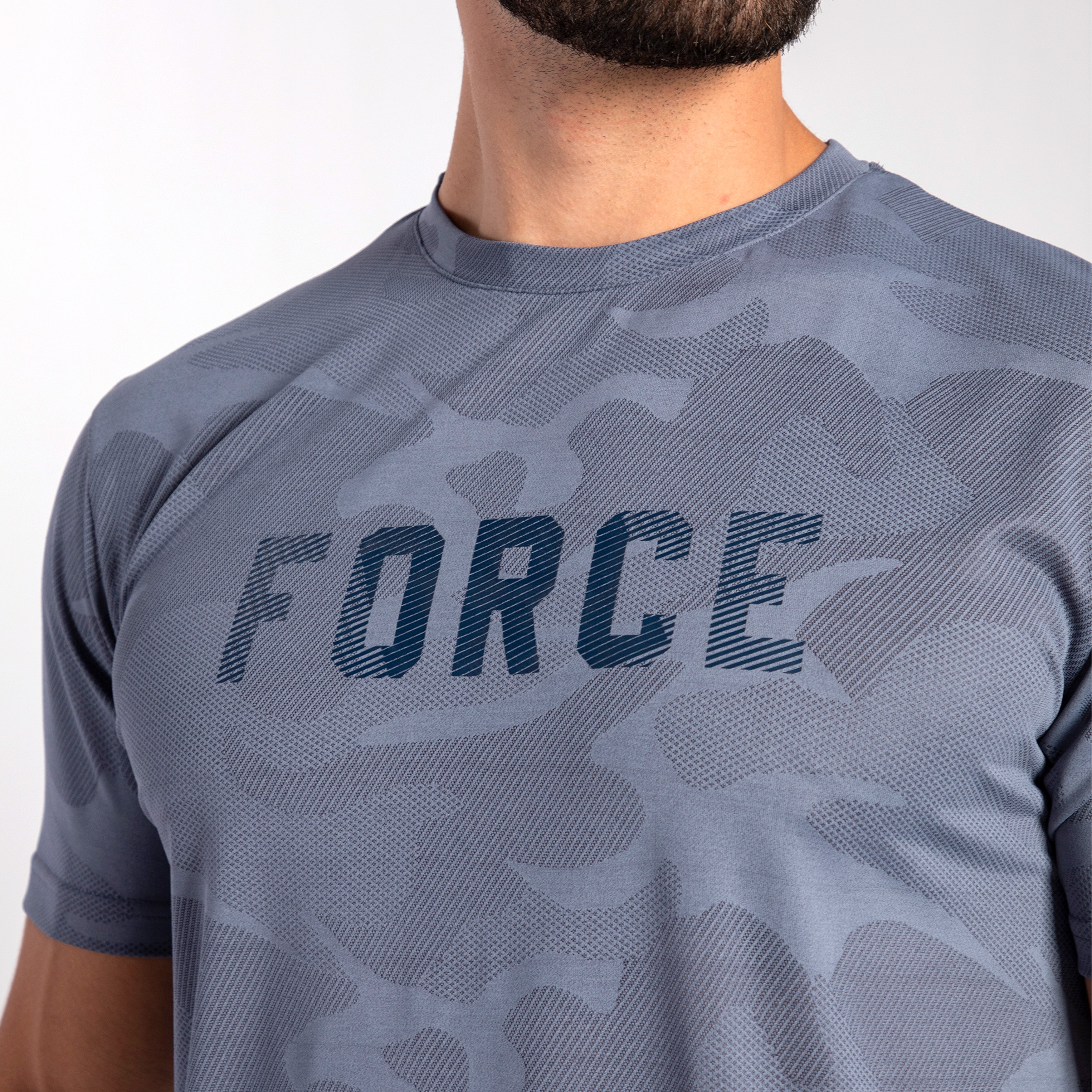 Close-up of a person wearing a gray camo-patterned athletic shirt with the word "FORCE" in bold letters. The mood is active and empowering.