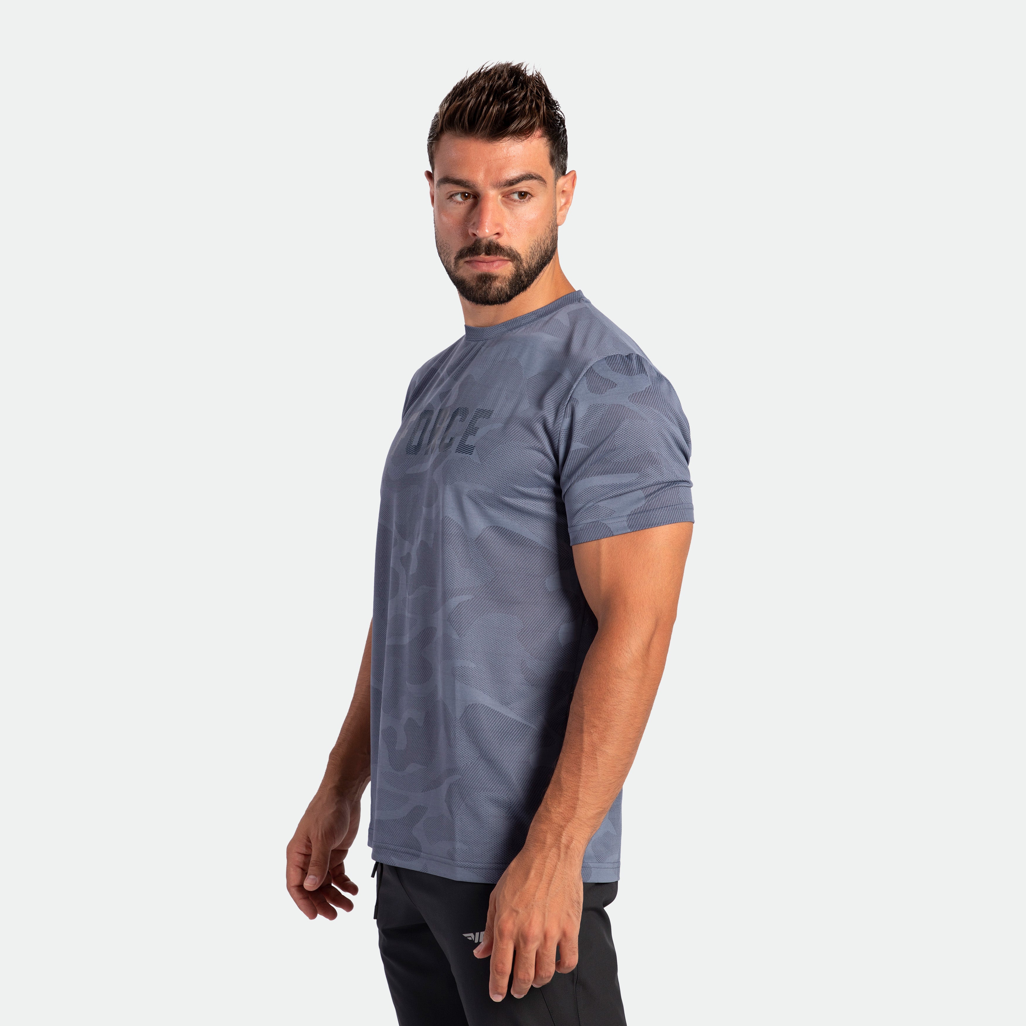 a fit man stand at right  and wearing camo t-shirt VINTAGE-INDIGO with pants black 